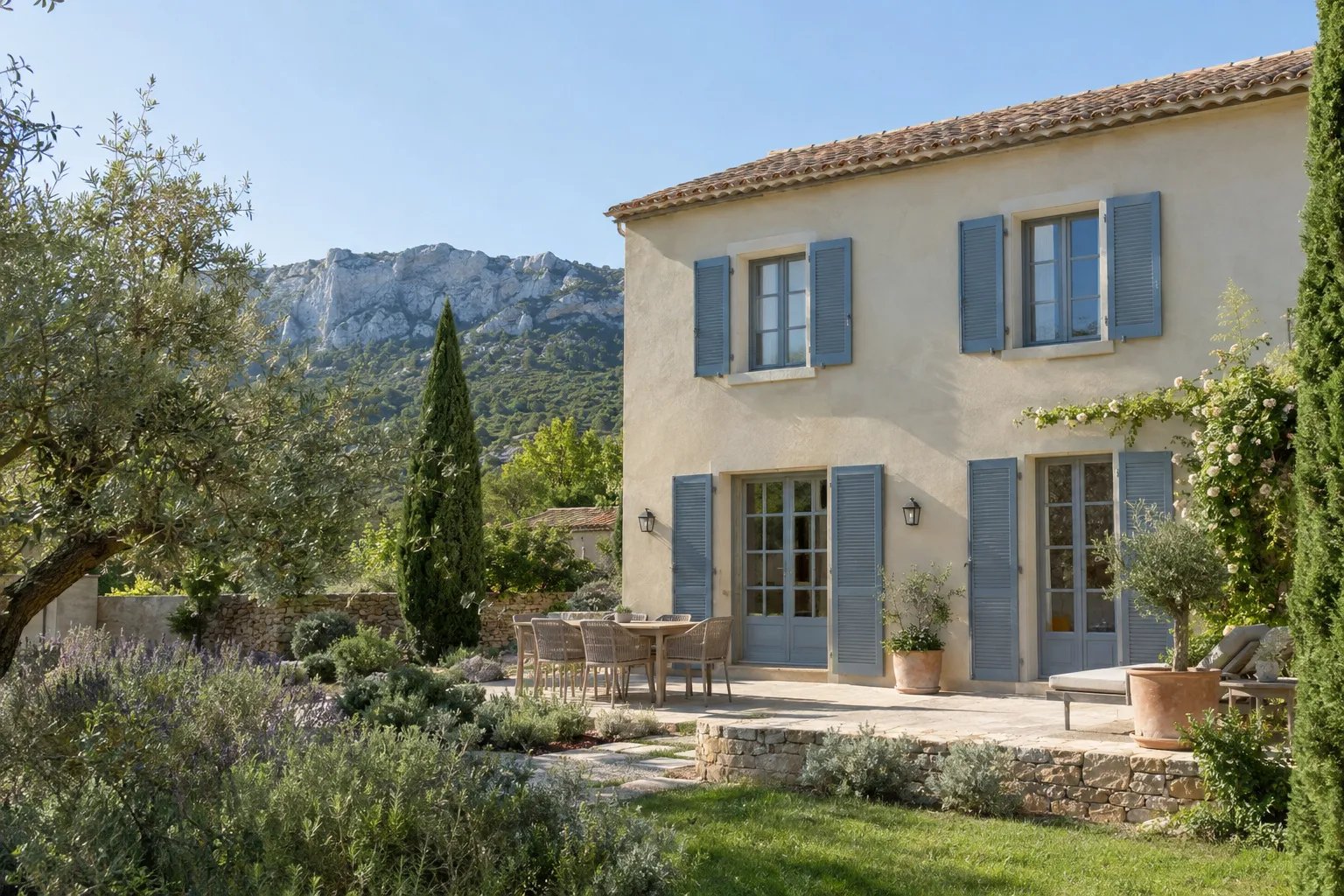 Bastide rénovée près d'Aubagne, façade enduite et volets bleu-gris, jardin d'oliviers et Garlaban en arrière-plan